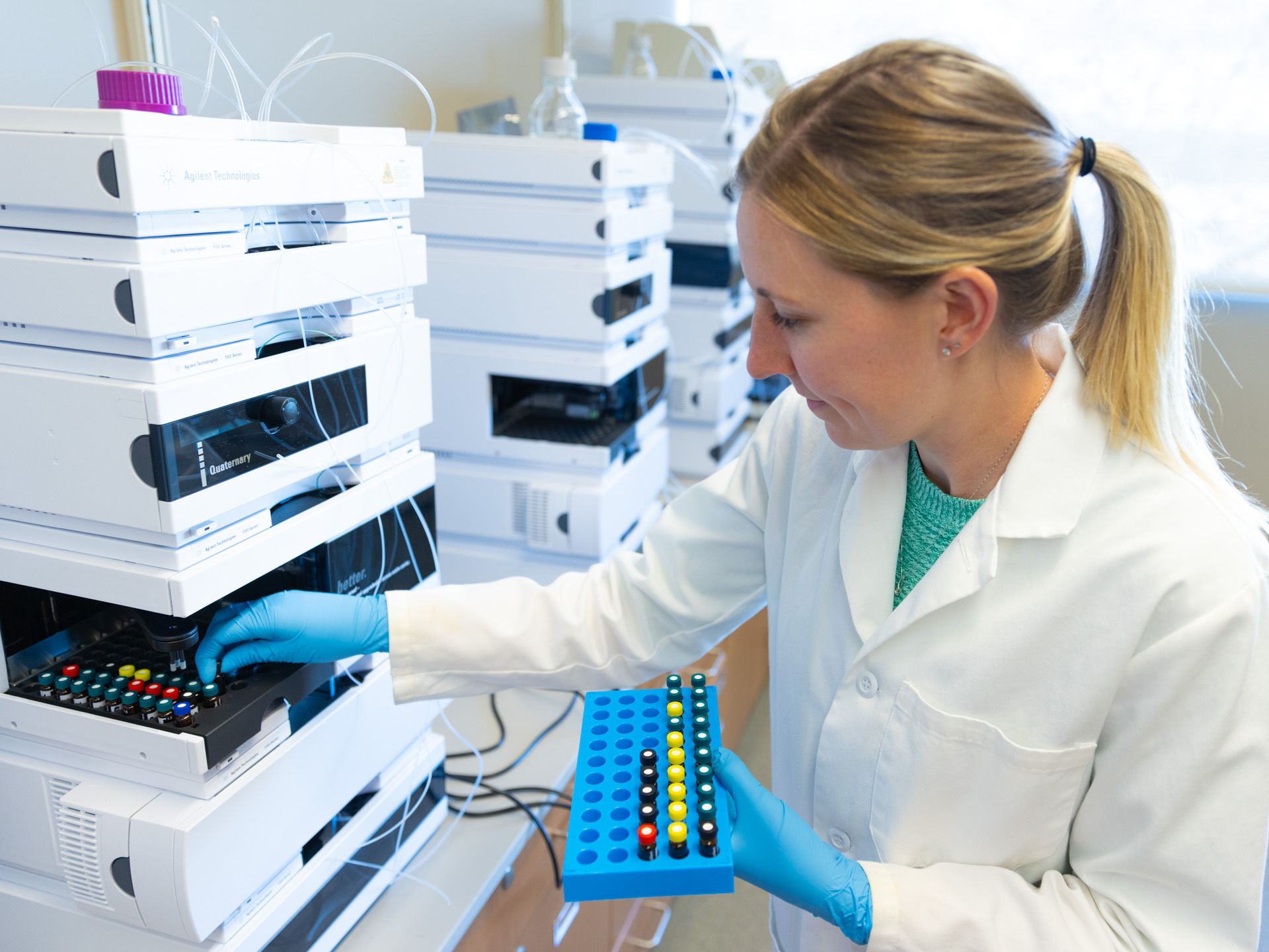 A blonde female scientist with blue gloves arranges devices at the Bioscience and Technology Business Incubator in Lawrence, KS.