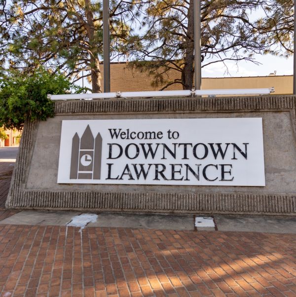 A stone sign that says "Welcome to Downtown Lawrence" greets those living in Lawrence, KS