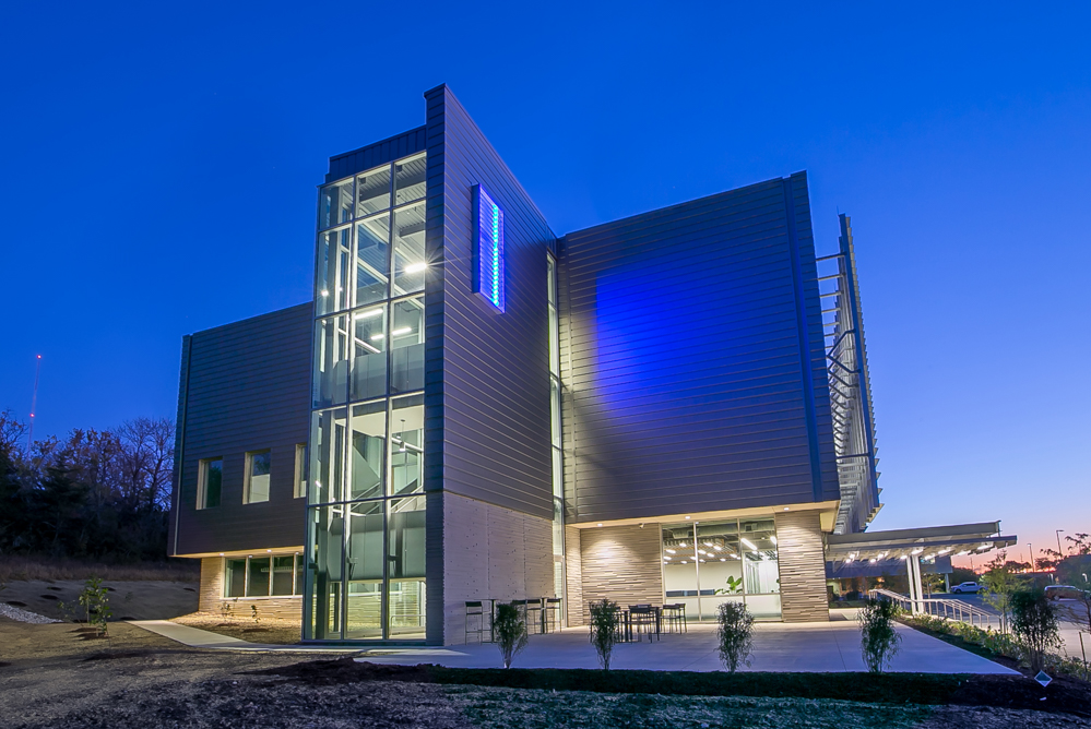 A modern building with blue LED lights from outside of the KU Innovation Park in Lawrence.