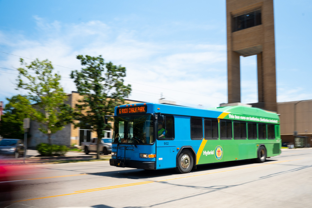 A blue and green KU bus drives through the streets of Lawrence.